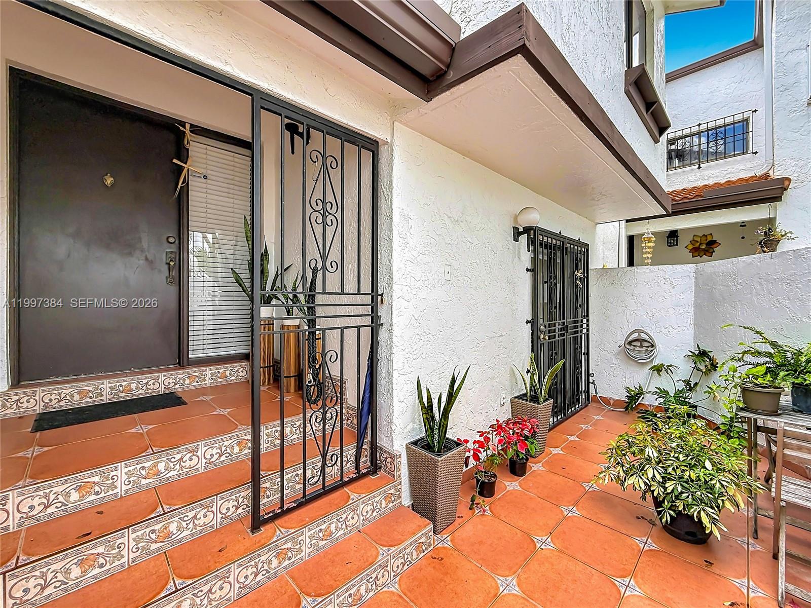 An exterior entryway features tiled steps, a metal security gate, and potted plants — 1291 SW 124th Ct # B, Miami FL 33184, MIAMI, FL