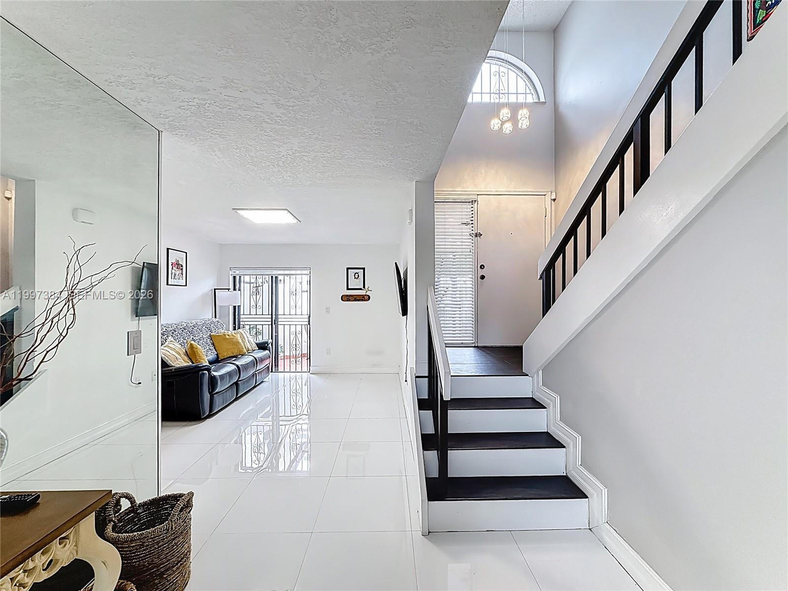 A bright living room features white tile floors, a staircase, and a glass sliding door — 1291 SW 124th Ct # B, Miami FL 33184, MIAMI, FL