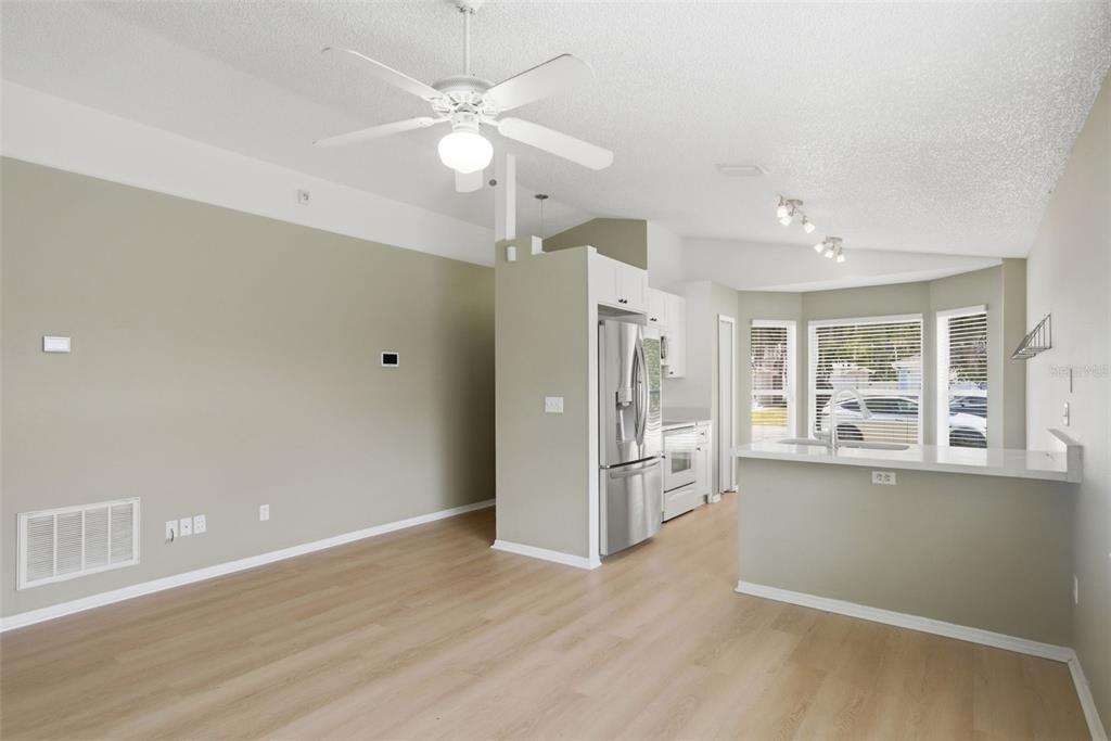 An open-concept kitchen and living area featuring light wood flooring, stainless appliances, and a ceiling fan — 2308 DONEGAN PLACE, ORLANDO, FL