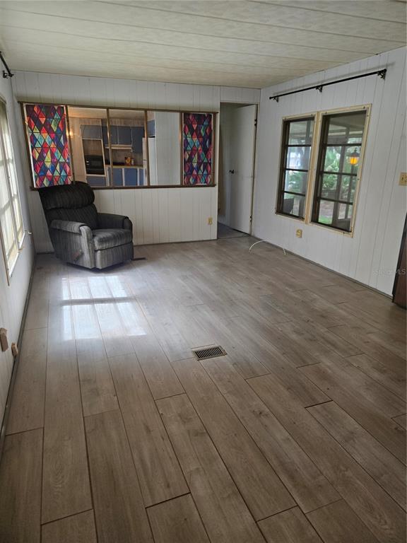 A living room with wood-look flooring, white paneling, a recliner, and a decorative pass-through window — 18927 SE 18TH PLACE, SILVER SPRINGS, FL