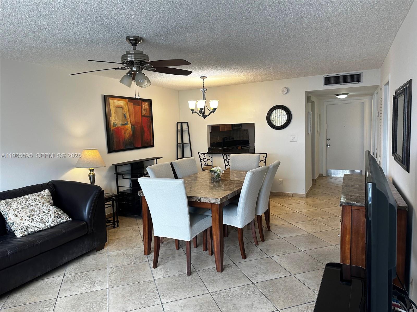 A dining area with a stone table and chairs sits adjacent to a living room — 410 SE 2nd St # 308, Hallandale Beach FL 33009, HALLANDALE BEACH, FL