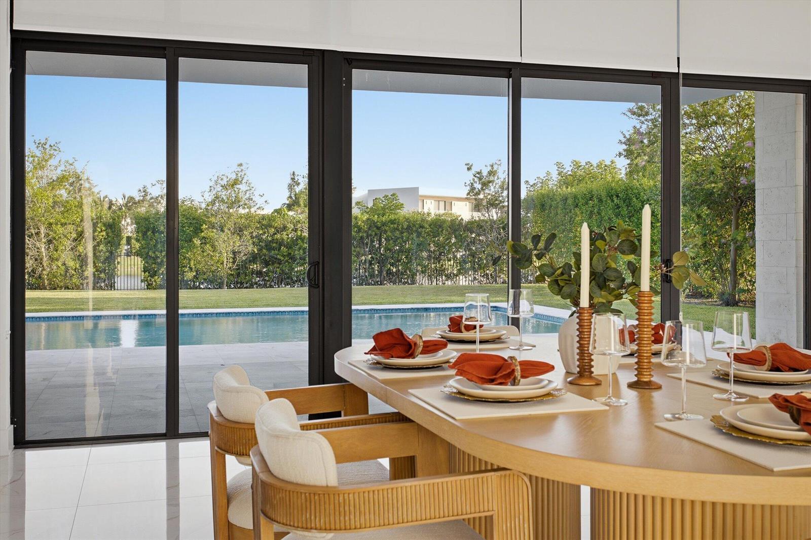A dining room with a wooden table overlooks a swimming pool through large sliding doors — 16570 Sunset Way, Weston FL 33326, WESTON, FL