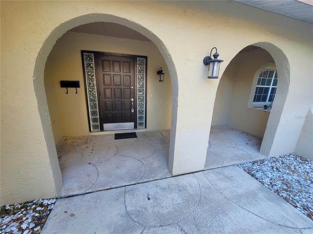 The front entrance features a dark door with glass block sidelights under two arched stucco openings — 622 GREEN MEADOW AVENUE, MAITLAND, FL
