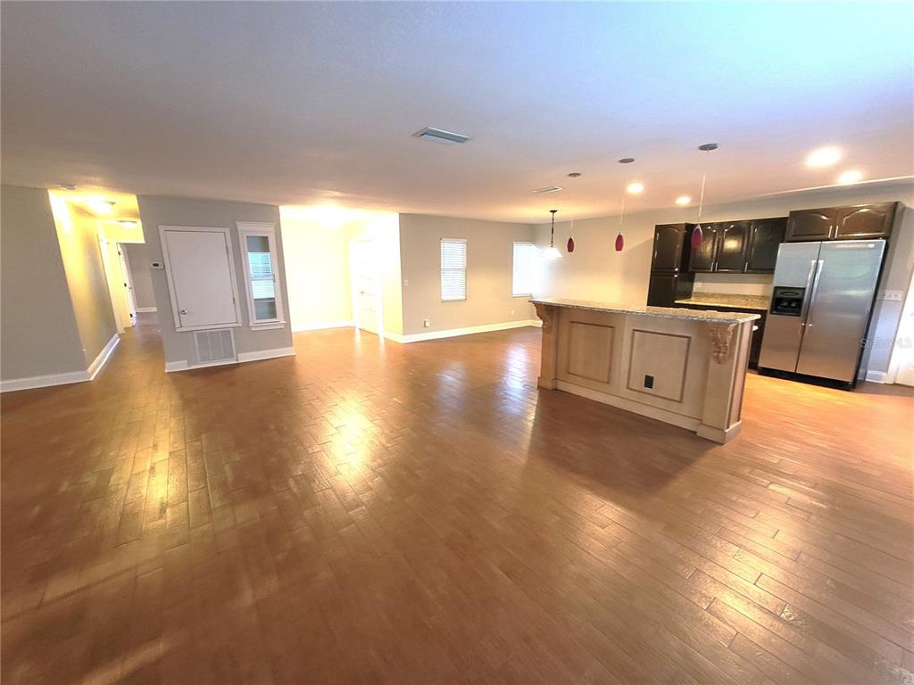 An open-concept kitchen and living area featuring hardwood floors, a granite-topped island, and stainless appliances — 622 GREEN MEADOW AVENUE, MAITLAND, FL