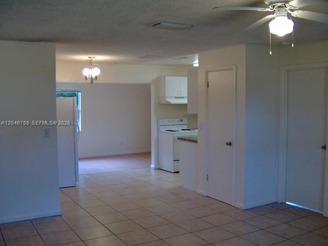 A tiled kitchen and dining area feature white cabinets, appliances, and a ceiling fan — PALM BEACH GARDENS, FL