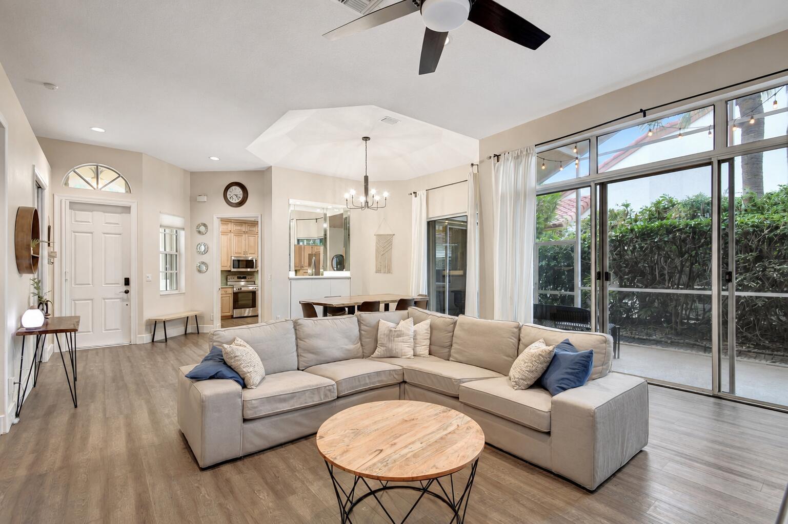A living room features a large sectional sofa, a round coffee table, and sliding glass doors — 23437 Water Circle, Boca Raton FL 33486, BOCA RATON, FL