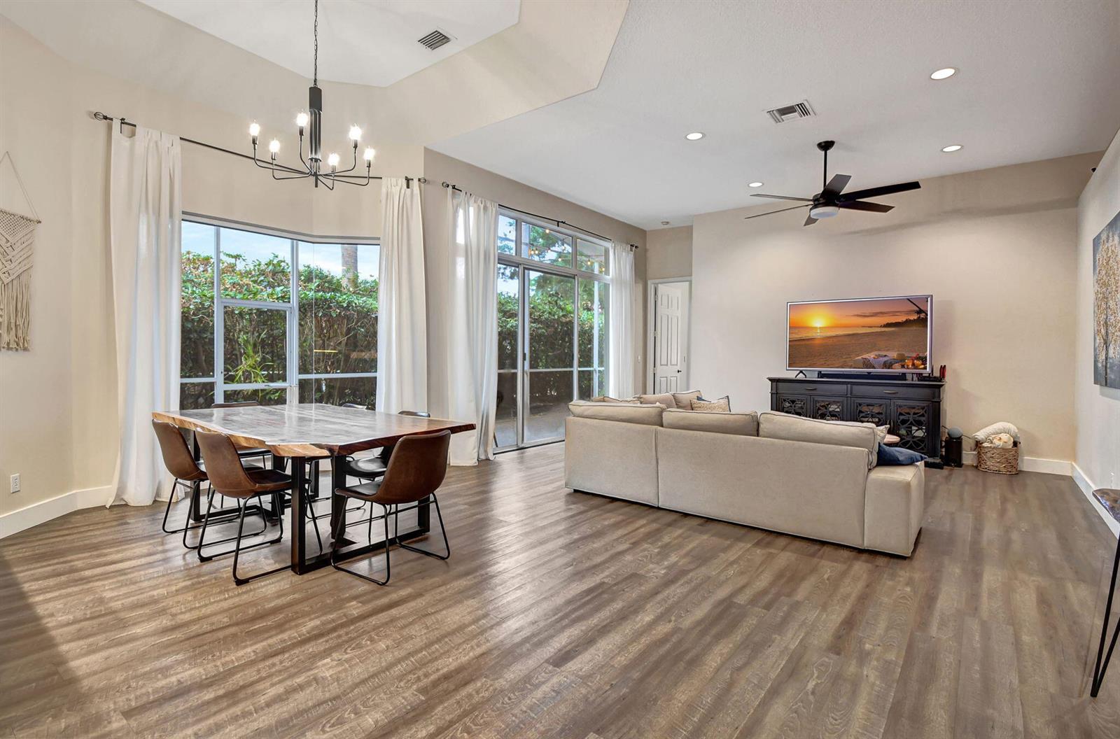 A living and dining area features wood-look flooring, a large sectional sofa, and a dining table — 23437 Water Circle, Boca Raton FL 33486, BOCA RATON, FL