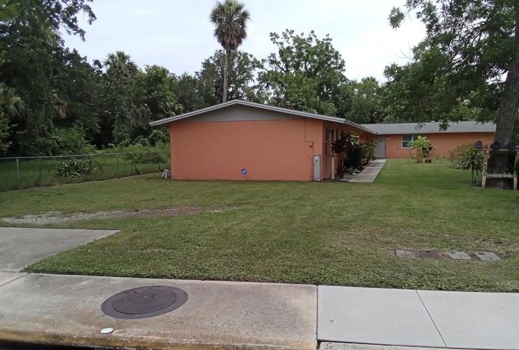 A single-story peach-colored building with a flat roof sits on a grassy lot — 555 OAK STREET, DAYTONA BEACH, FL