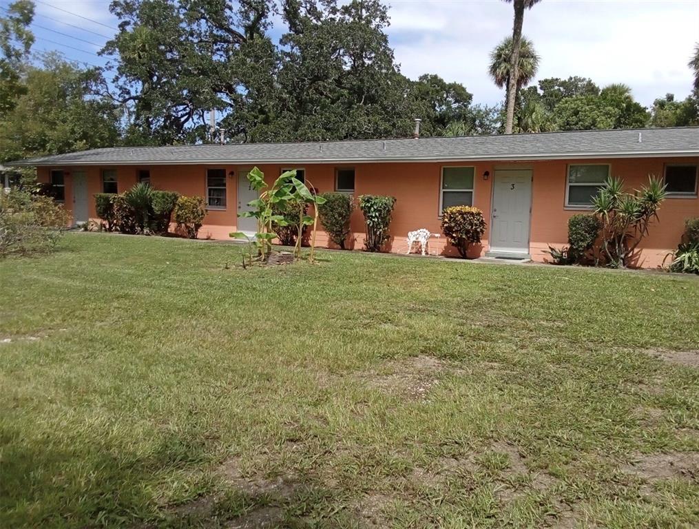A single-story peach-colored apartment building features multiple entry doors and a grassy front yard — 555 OAK STREET, DAYTONA BEACH, FL