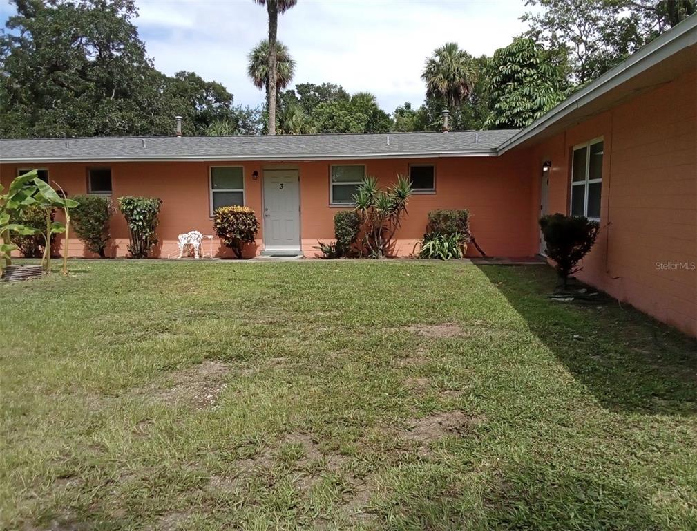 A peach-colored single-story building features a grassy yard and several small windows and doors — 555 OAK STREET, DAYTONA BEACH, FL
