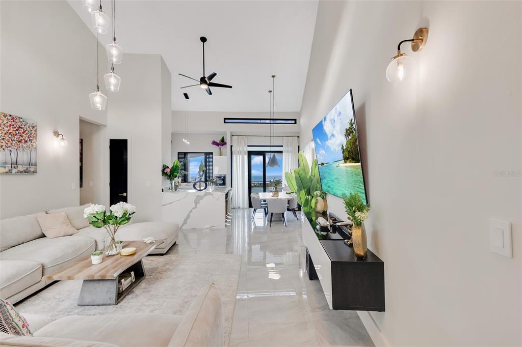A modern, open-concept living and dining area features high ceilings, marble floors, and a large television — 6000 RIO MAR BOULEVARD UNIT 7131, RIO GRANDE, PR