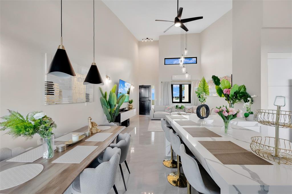 A modern open-concept dining and kitchen area features high ceilings, tile floors, and pendant lighting — 6000 RIO MAR BOULEVARD UNIT 7131, RIO GRANDE, PR
