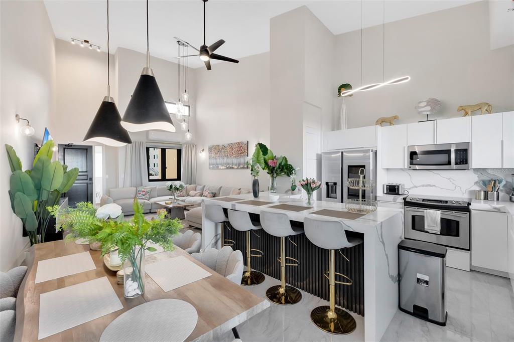 An open-concept kitchen and dining area features a marble island, bar stools, and vaulted ceilings — 6000 RIO MAR BOULEVARD UNIT 7131, RIO GRANDE, PR