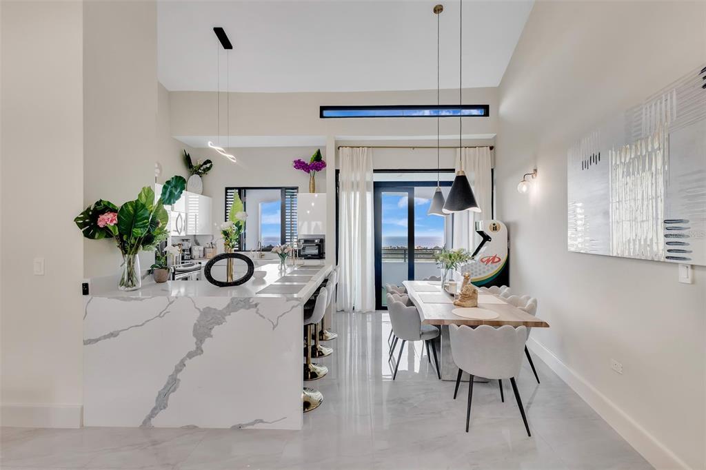A modern kitchen and dining area features a marble island, pendant lighting, and balcony views — 6000 RIO MAR BOULEVARD UNIT 7131, RIO GRANDE, PR