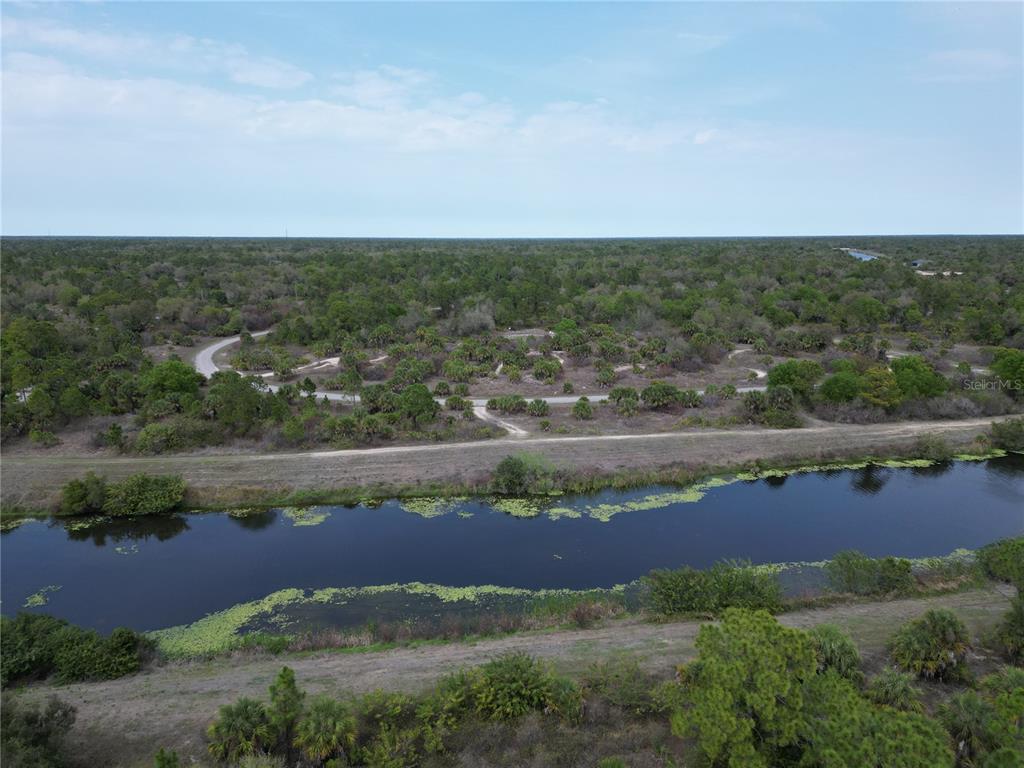 An aerial view shows a canal in the foreground and a wooded lot beyond — S RAINTREE BOULEVARD, NORTH PORT, FL