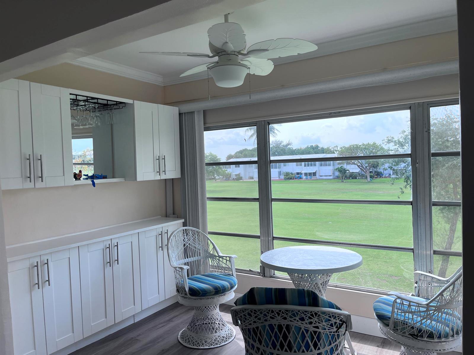 A sunroom features white cabinetry, a ceiling fan, wicker furniture, and large windows overlooking grass — 251 S Golf # 294, Pompano Beach FL 33064, POMPANO BEACH, FL