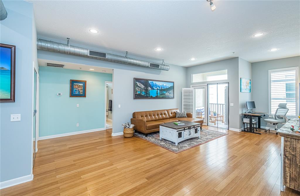 A living room features light blue walls, hardwood floors, a brown leather sofa, and exposed ductwork — 535 4TH AVENUE S UNIT 4, ST PETERSBURG, FL