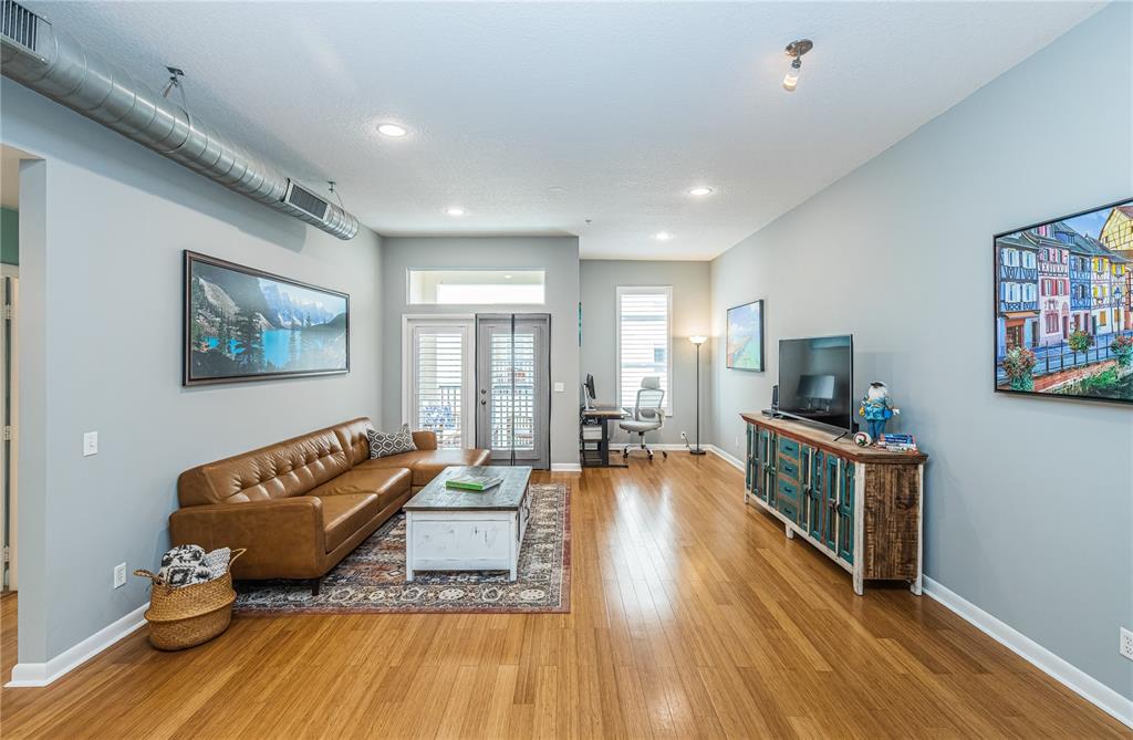 A living room features a brown leather sofa, wood flooring, and an exposed ceiling duct — 535 4TH AVENUE S UNIT 4, ST PETERSBURG, FL