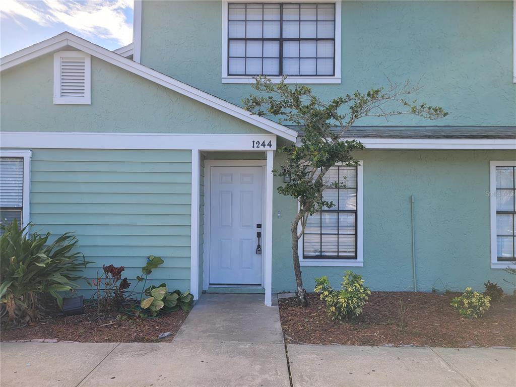 The exterior of a two-story teal house features a white front door and a walkway — 1236 DOVEHILL DRIVE UNIT 1244, APOPKA, FL