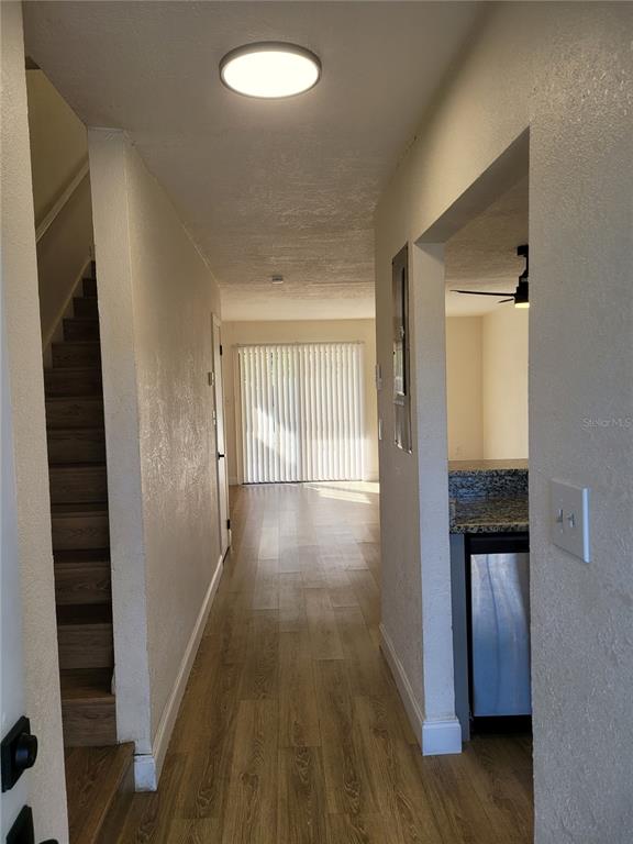 A view from an entryway showing stairs, wood-look flooring, and a kitchen with granite countertops — 1236 DOVEHILL DRIVE UNIT 1244, APOPKA, FL