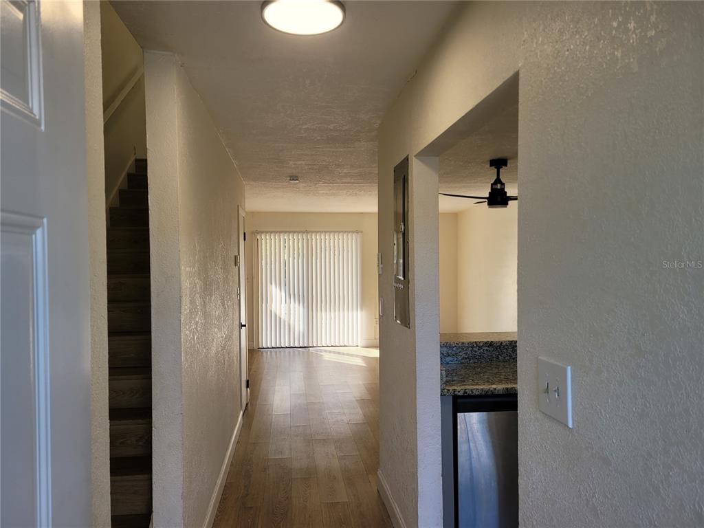 A hallway leads to a living area with sliding glass doors and an adjacent kitchen — 1236 DOVEHILL DRIVE UNIT 1244, APOPKA, FL