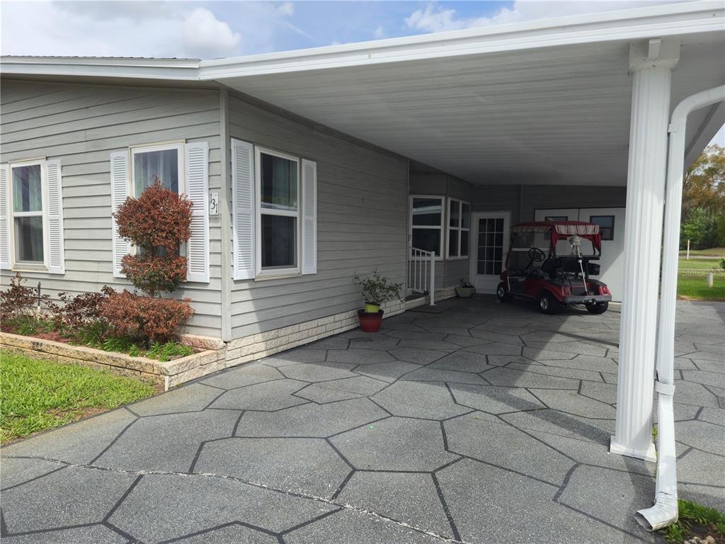 A light gray manufactured home features a patterned concrete driveway and a covered carport — 131 VICTORIA DRIVE, HAINES CITY, FL