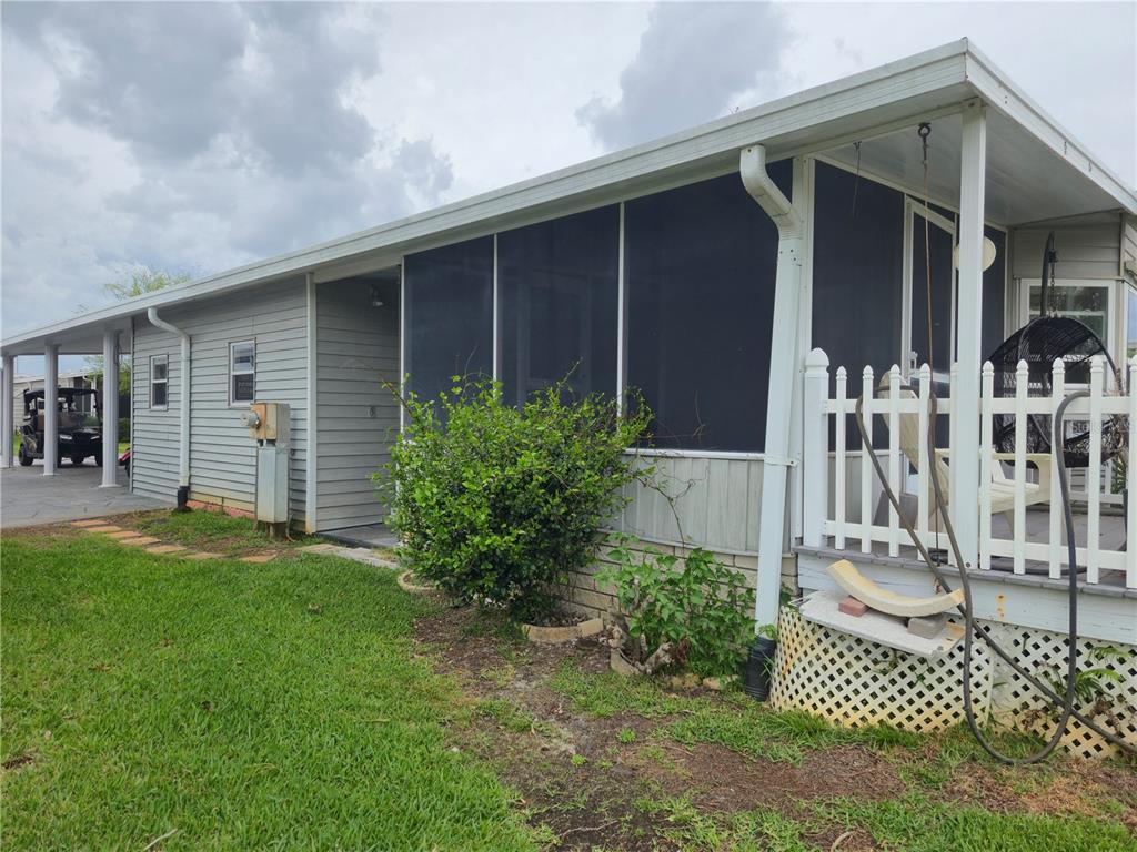 The exterior of a manufactured home features a screened-in porch, white lattice skirting, and siding — 131 VICTORIA DRIVE, HAINES CITY, FL