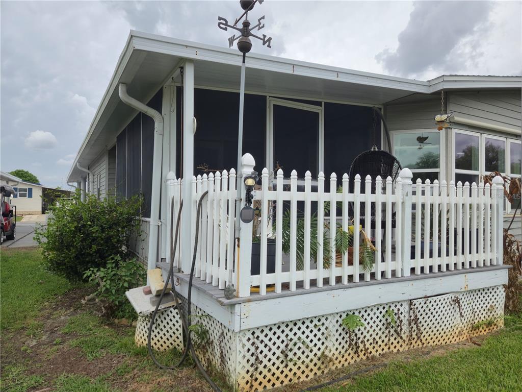 A white picket fence surrounds a raised wooden deck attached to a mobile home — 131 VICTORIA DRIVE, HAINES CITY, FL