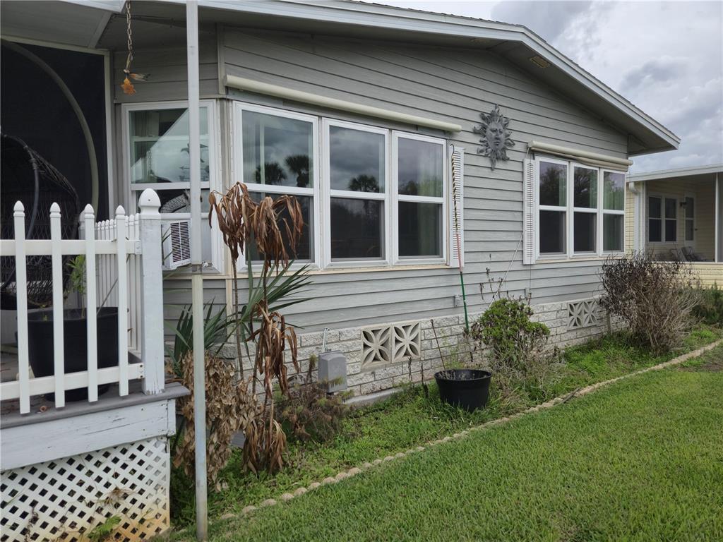 The exterior of a light gray manufactured home features white-trimmed windows and a lattice skirt — 131 VICTORIA DRIVE, HAINES CITY, FL