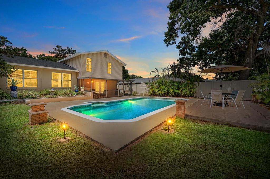 A backyard features a swimming pool with a raised concrete edge and a patio area — 709 CALIENTE DRIVE, BRANDON, FL