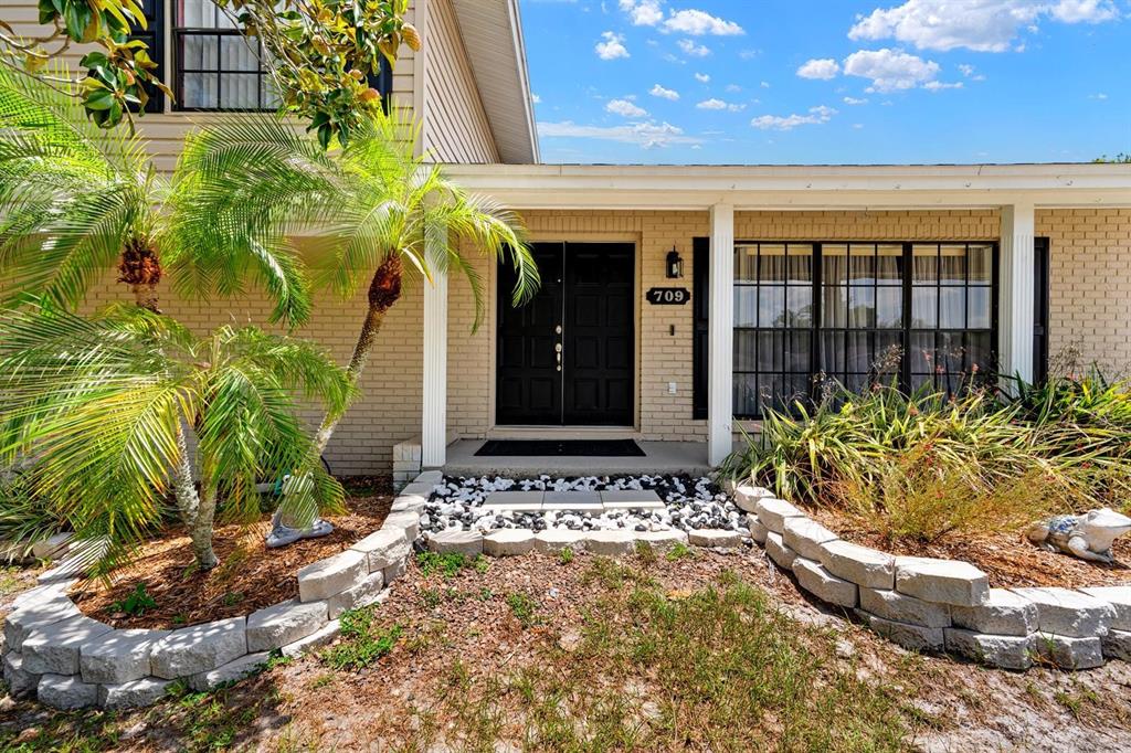 The exterior of a house features a brick facade, a double front door, and landscaping — 709 CALIENTE DRIVE, BRANDON, FL