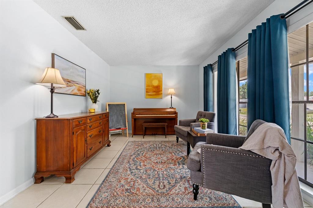 A living room features a wooden piano, a sideboard, two armchairs, and a patterned rug — 709 CALIENTE DRIVE, BRANDON, FL