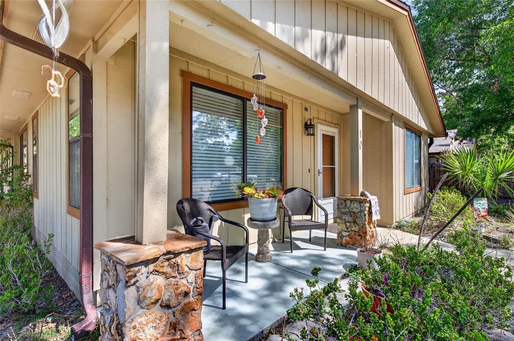 A covered front porch features stone pillars, two chairs, and a small table with plants — 10 LAKEPOINT CIRCLE, PORT ORANGE, FL
