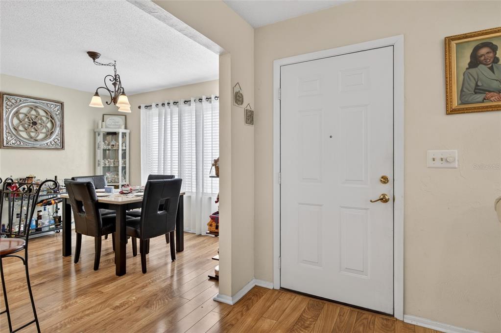 An entryway with a white door leads into a dining area with wood-look flooring — 10 LAKEPOINT CIRCLE, PORT ORANGE, FL