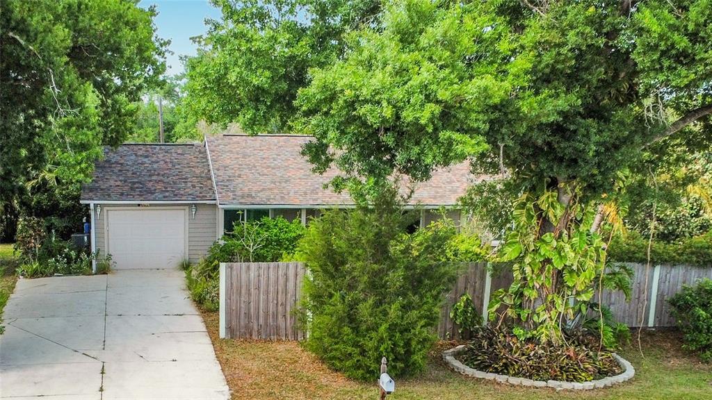 A single-story house with a garage and a wooden fence stands behind a large tree — 601 E SEMINOLE DRIVE, VENICE, FL