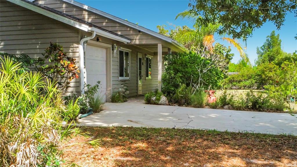 A single-story house with beige siding, a white garage door, and a concrete driveway — 601 E SEMINOLE DRIVE, VENICE, FL