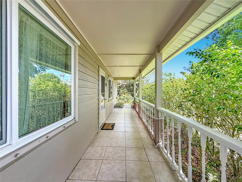 A covered porch with tiled flooring, white railings, and light-colored siding along the exterior wall — 601 E SEMINOLE DRIVE, VENICE, FL