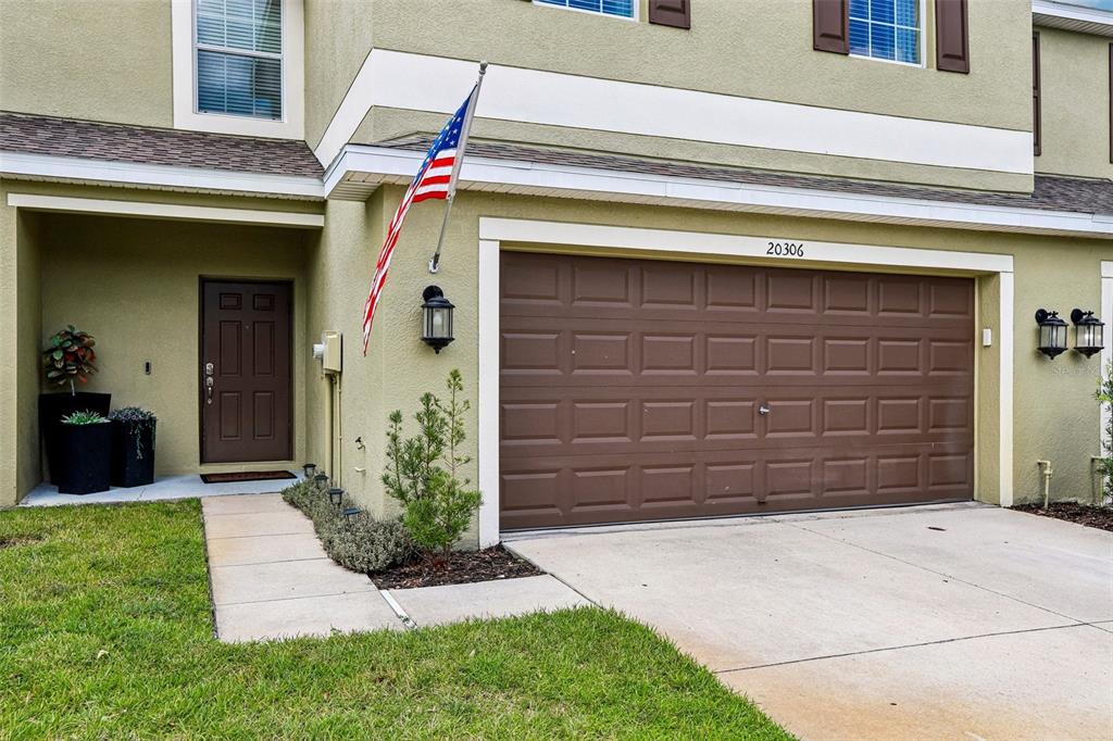 The exterior of a two-story townhouse features a brown garage door and a front entrance — 20306 STARFINDER WAY, TAMPA, FL