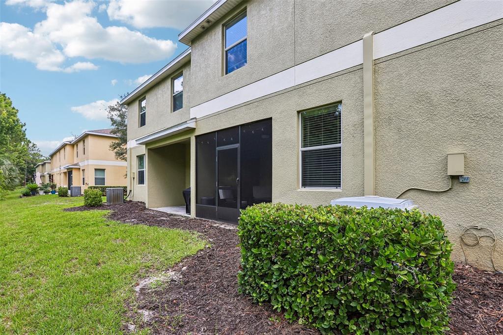 The exterior of a two-story stucco townhouse features a screened-in patio and a small hedge — 20306 STARFINDER WAY, TAMPA, FL