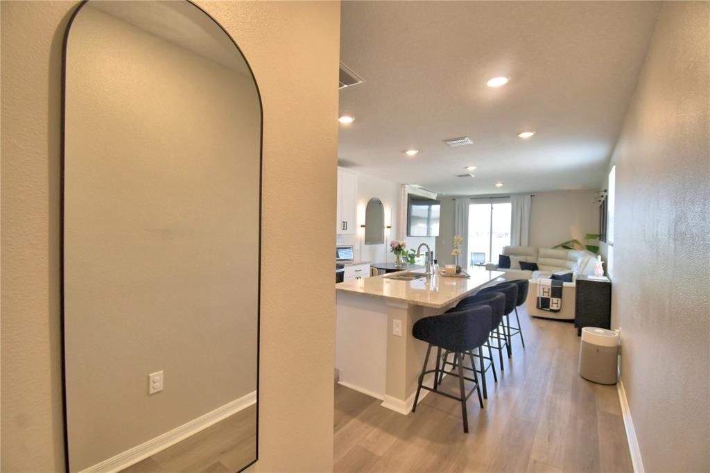 A view from a hallway into an open-concept kitchen and living area with bar seating — 3563 BROADWING BOULEVARD, KISSIMMEE, FL