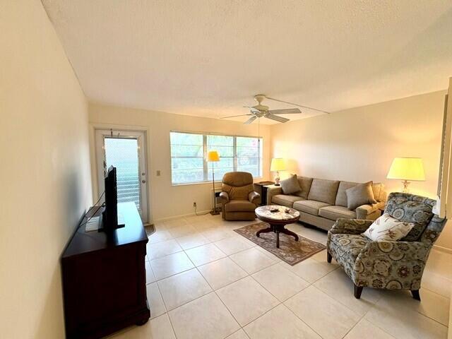 A living room features tile flooring, a beige sofa, two armchairs, and a ceiling fan — 116 Windsor F, West Palm Beach FL 33417, WEST PALM BEACH, FL