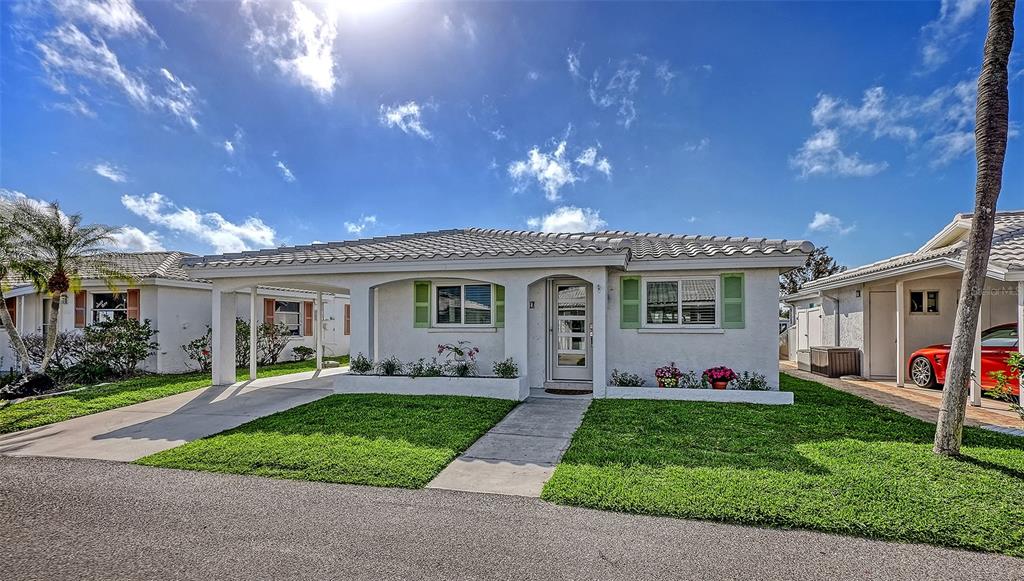 A single-story house with a carport, light-colored stucco walls, and green shutters under a blue sky — 900 SPANISH DRIVE N, LONGBOAT KEY, FL