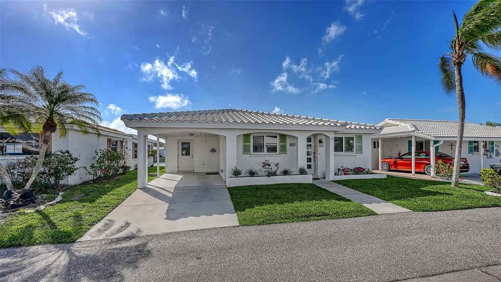 A white single-story house with a carport, green shutters, and palm trees under blue skies — 900 SPANISH DRIVE N, LONGBOAT KEY, FL