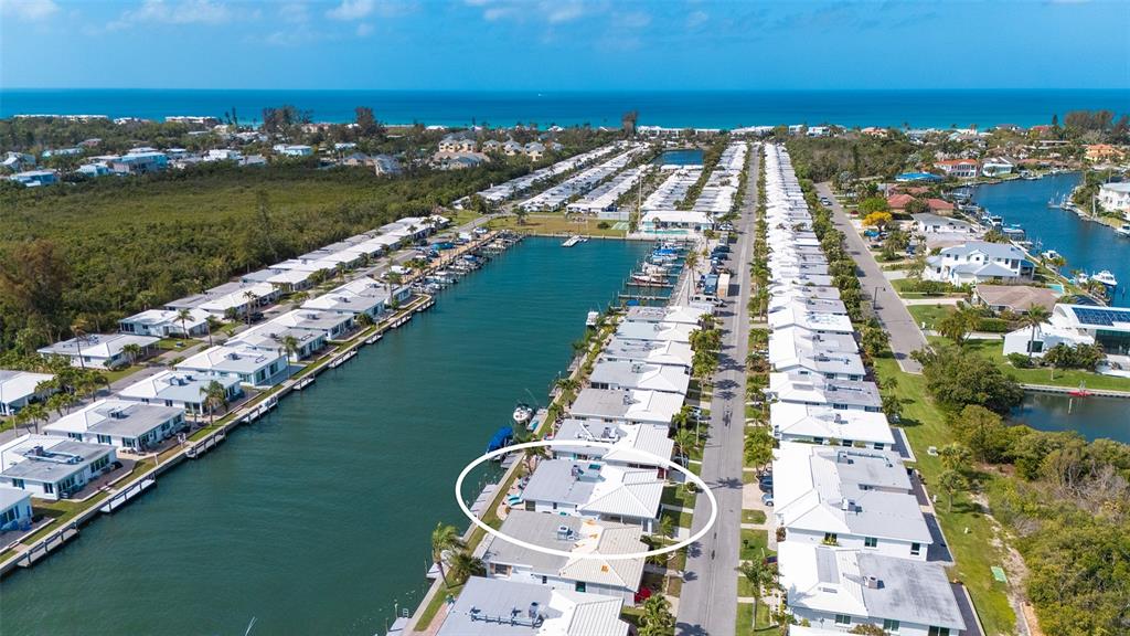 An aerial view shows a waterfront residential community with a circled house along a canal — 900 SPANISH DRIVE N, LONGBOAT KEY, FL