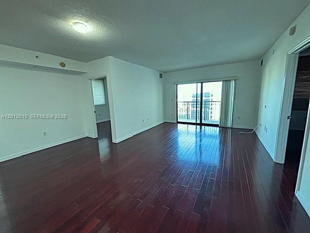 An empty room features dark wood flooring, white walls, and a sliding glass door — 4242 NW 2nd St # 901, Miami FL 33126, MIAMI, FL