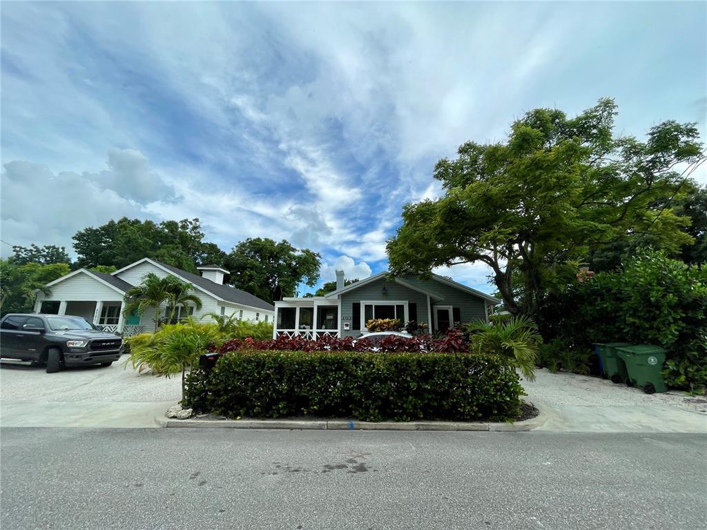 A gray house with a screened porch and a large hedge sits behind a street — 2703 10TH AVENUE W, BRADENTON, FL