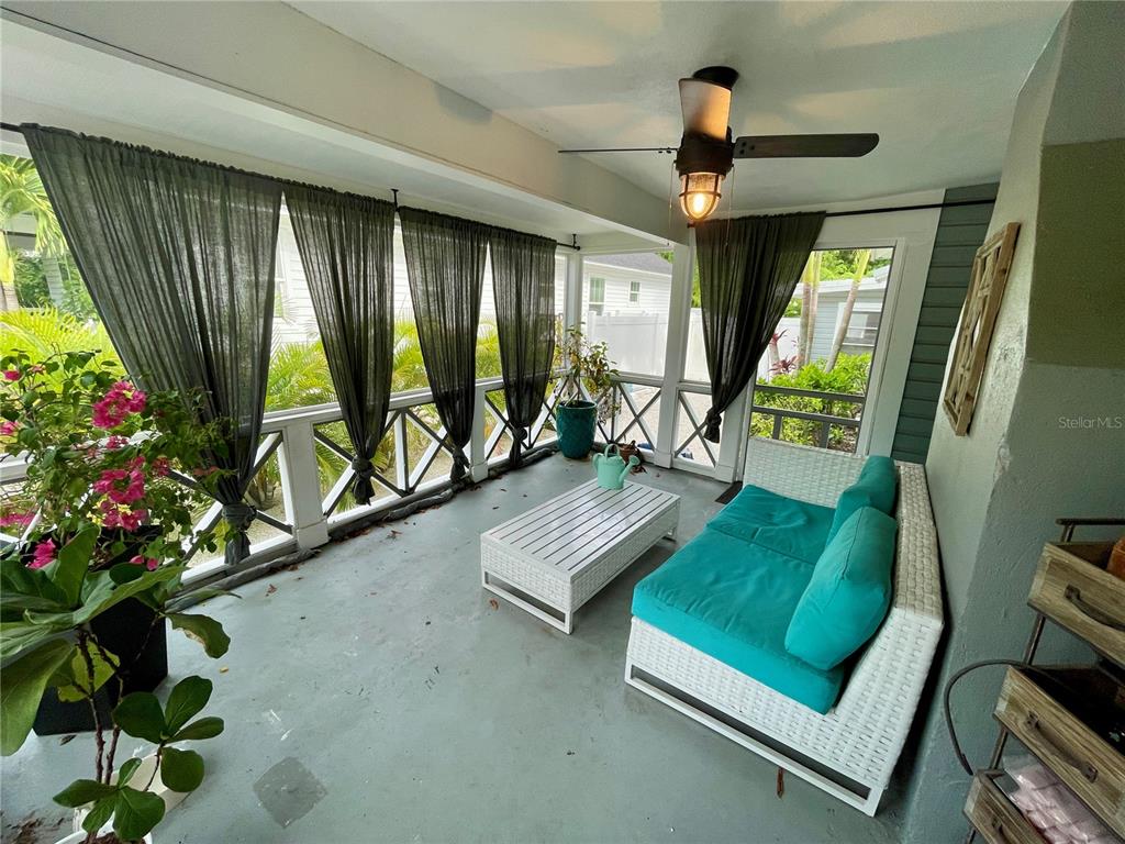 A screened-in porch features a white wicker sofa with teal cushions and a matching table — 2703 10TH AVENUE W, BRADENTON, FL