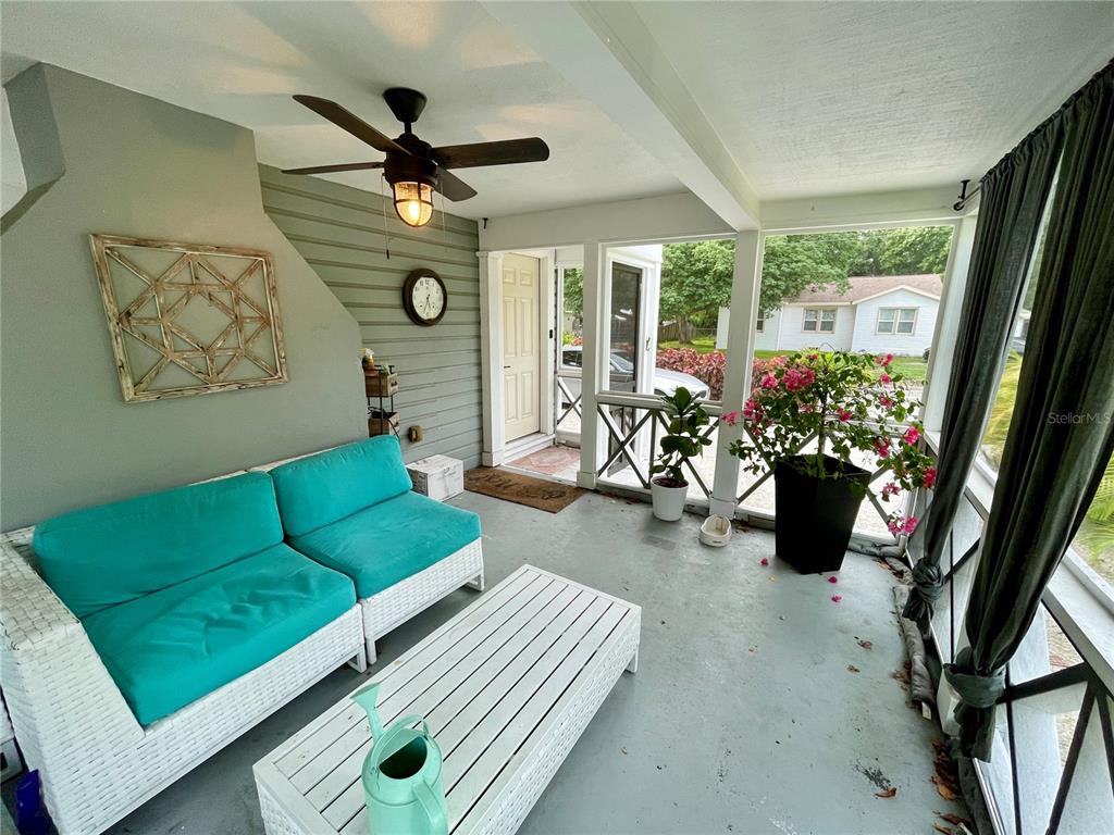 A screened-in porch features a turquoise sofa, white coffee table, and a ceiling fan — 2703 10TH AVENUE W, BRADENTON, FL