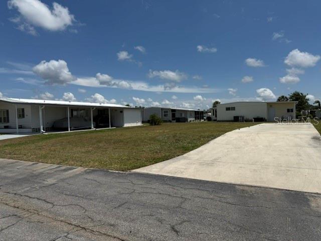 A long, white manufactured home sits next to a large concrete driveway under a blue sky — 657 ALVARADO, NORTH PORT, FL