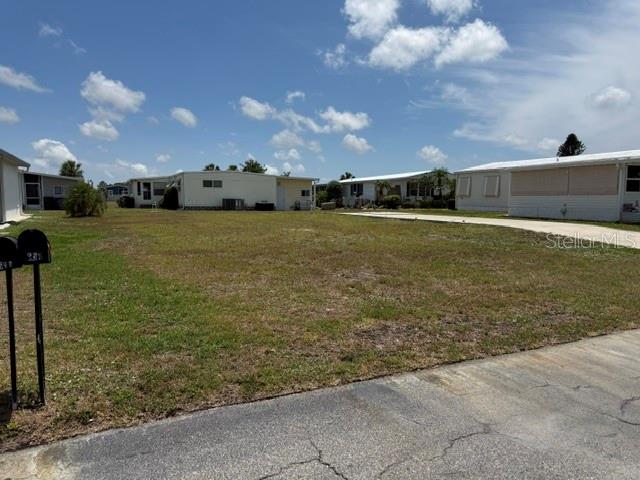 A vacant, grassy lot sits between two manufactured homes under a partly cloudy sky — 657 ALVARADO, NORTH PORT, FL